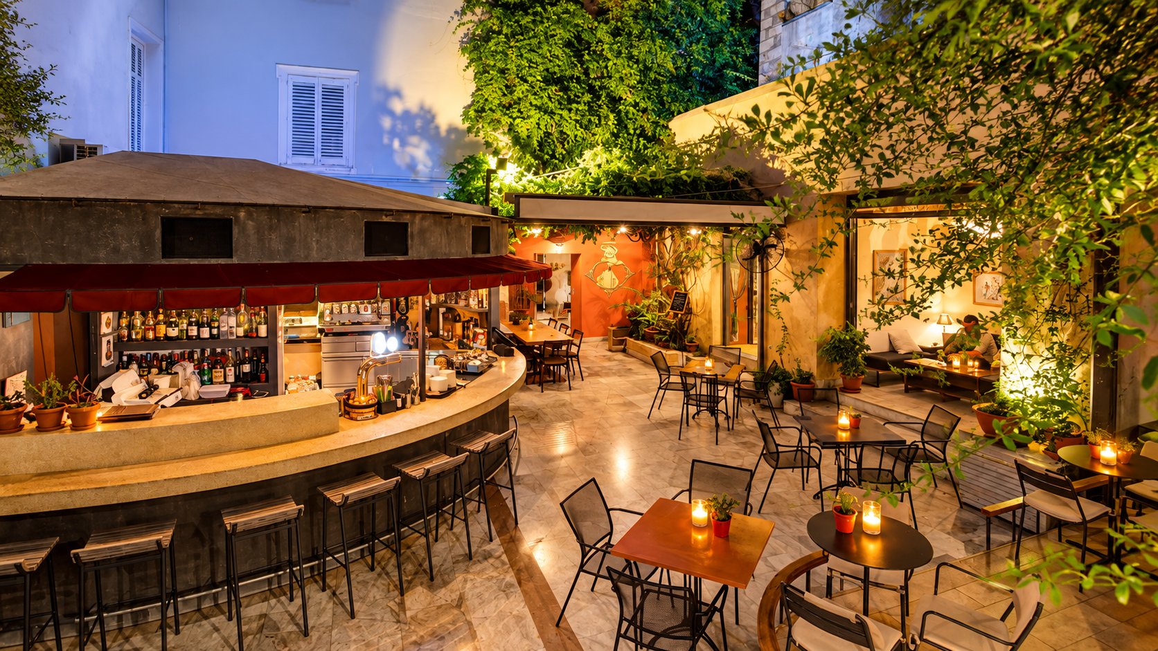The candlelit courtyard of Black Duck Garden at dusk, with its bar and tables beneath the greenery